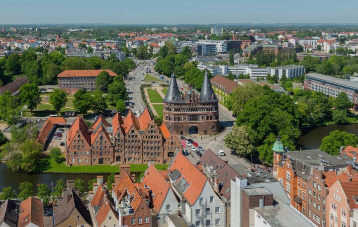 7. Platz. Blick vom Turm der St.-Petri-Kirche über den Holstentorplatz mit dem berühmten Holstentor in der Altstadt von Lübeck in Schleswig-Holstein. Die Gebäude links neben dem Holstentor sind die Lübecker Salzspeicher.